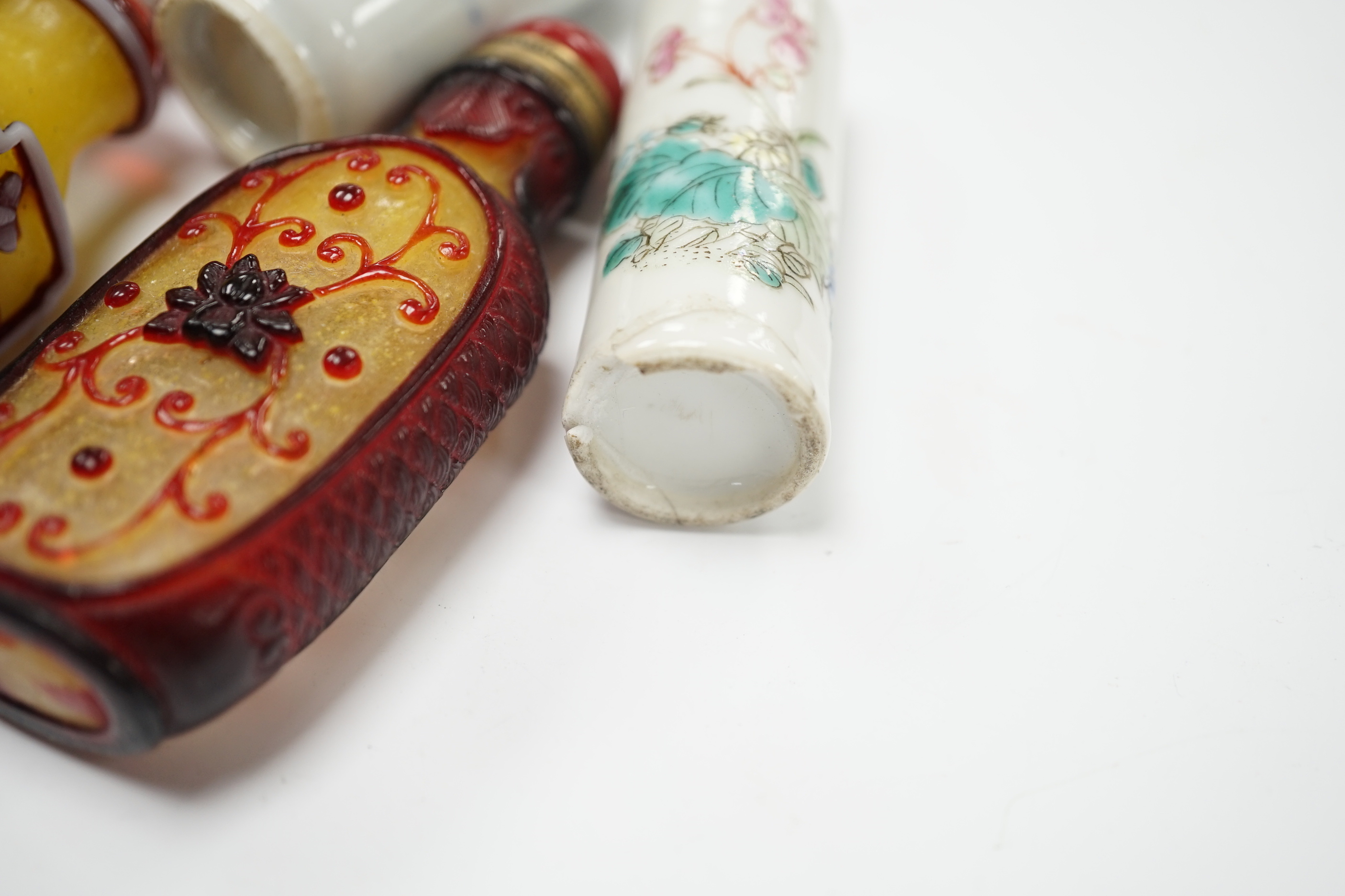 Four Chinese overlaid glass snuff bottles and two Chinese porcelain snuff bottles, three with stoppers, largest 9cm high